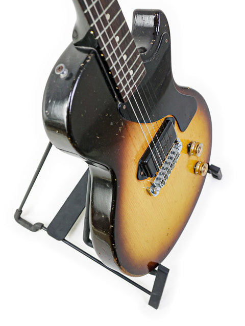 A classic 1958 Gibson Les Paul Jr TV Yellow Refin guitar resting on a stand, set against a dark background.