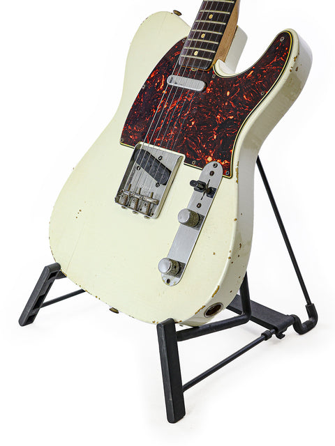 A classic 1963 Fender Telecaster guitar, white with a black pick guard, showcased on a stand.