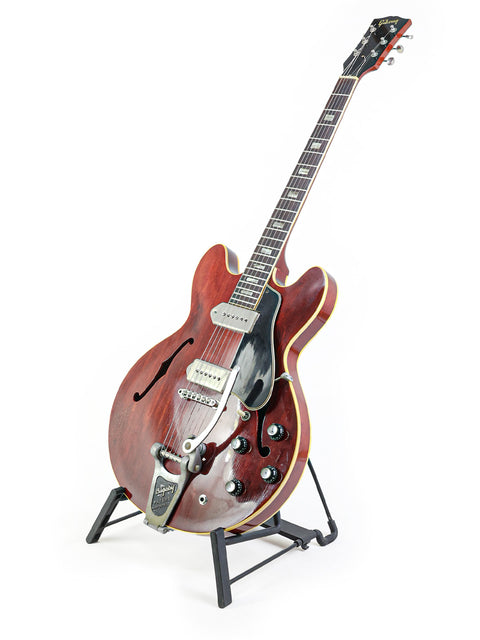 A classic 1965 Gibson ES-330 guitar on a stand, representing vintage American craftsmanship in music.