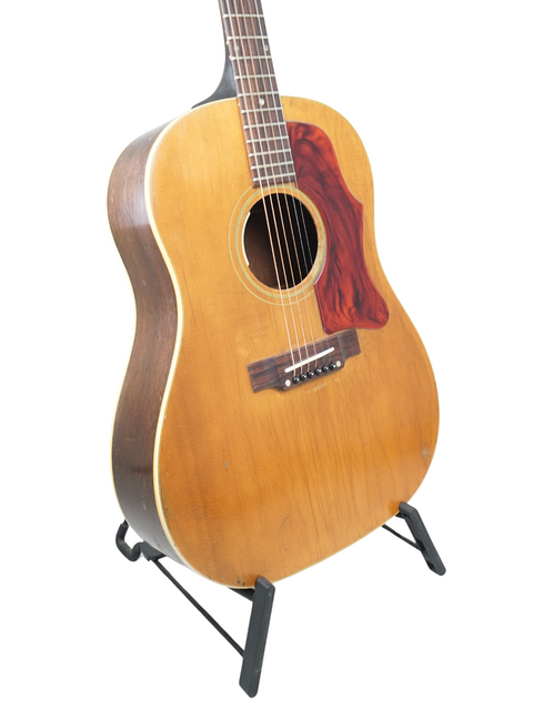 A classic 1968 Gibson J-50 guitar on a stand, beautifully showcased against a bright white backdrop.