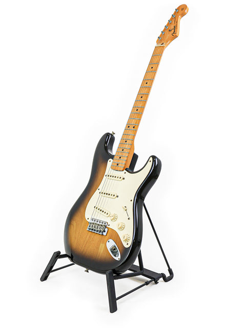 A classic 1982 Fender AVRI ‘57 Stratocaster guitar displayed on a stand with a simple white backdrop.