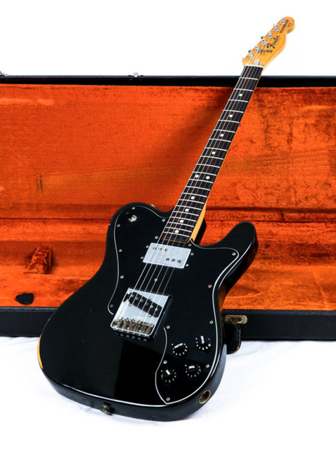 A classic black electric guitar, the 1978 Fender Telecaster Custom, nestled in a vibrant orange case, highlighting its elegance.
