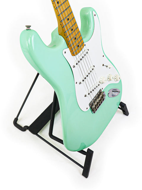 A classic green Fender AVRI '57 Stratocaster from 1985, proudly standing on its display stand.
