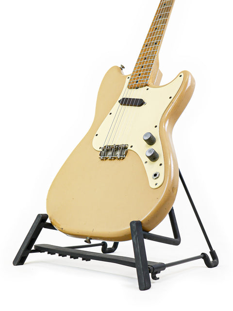 A classic tan Fender Musicmaster guitar from 1957, resting on a stand with a simple white background for a timeless look.