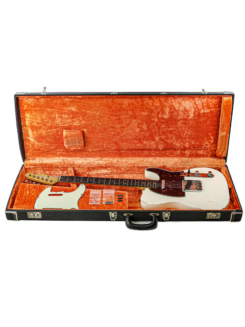 A classic white electric guitar, a 1963 Fender Telecaster, elegantly placed in an orange case, emphasizing its vintage appeal.