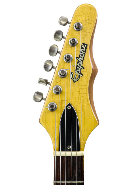 A close-up view of a vintage 1964 Epiphone Crestwood Custom guitar, highlighting its unique yellow headstock.