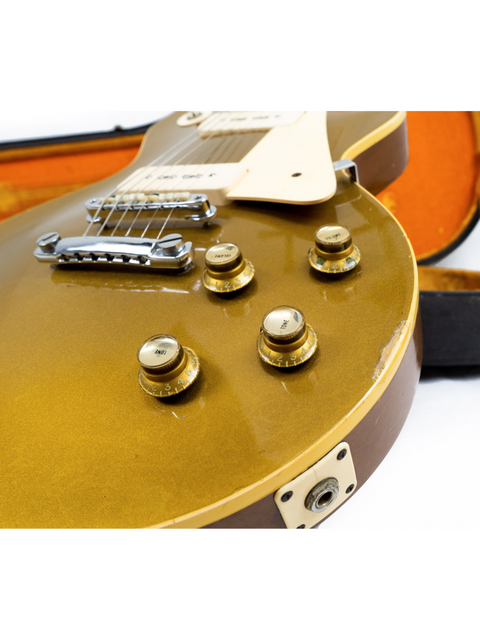 A gold Gibson Les Paul guitar from 1968, featuring a narrow headstock, accompanied by a case and a stylish guitar strap.