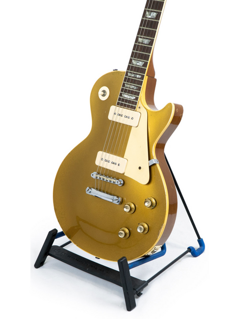A gold electric guitar, specifically a 1968 Gibson Les Paul Standard Goldtop, prominently positioned on a stand.