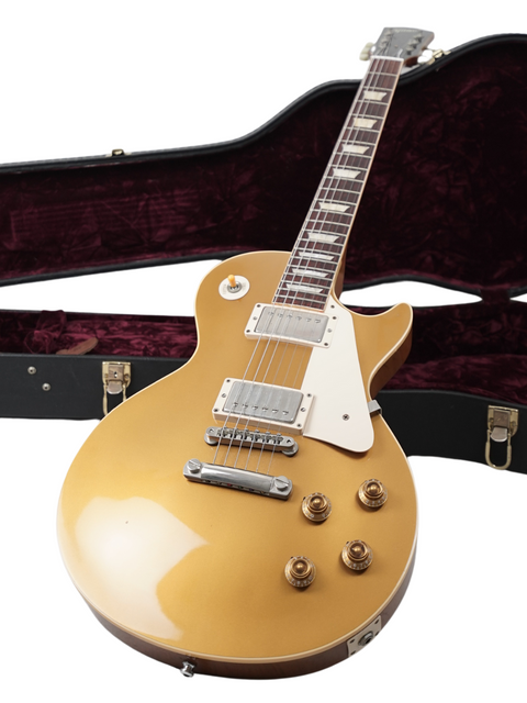 A gold guitar and its case, displaying the Gibson Custom Shop LPR-7 1957 Les Paul Goldtop Reissue, all on a white background.