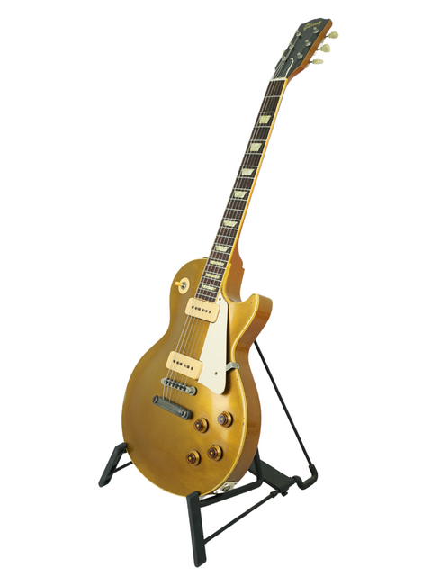 A golden 1956 Gibson Les Paul guitar on a stand, highlighting its relic design and exquisite craftsmanship.