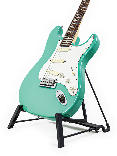 A green 1989 Fender Strat Plus Deluxe electric guitar resting on a stand, highlighting its classic design and color.
