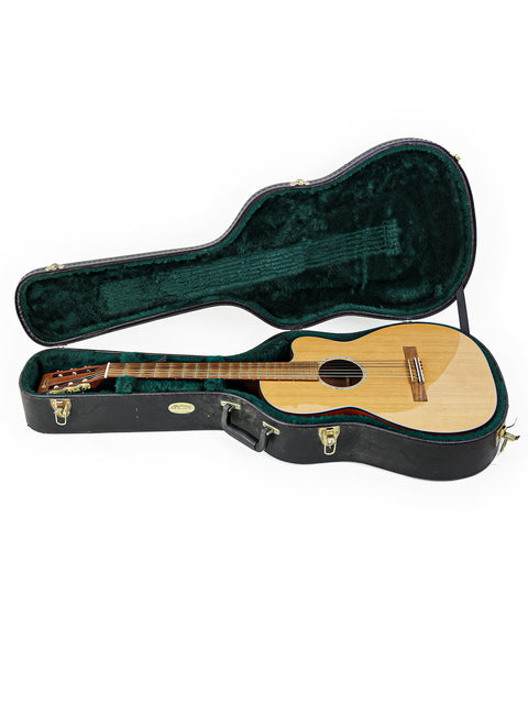 A green guitar case holds a wooden Martin 000C-16SGCTNE guitar from the USA, crafted in 2003, showcasing its elegant design.