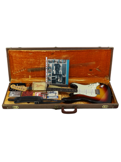 A guitar case opens to reveal a 1961 Fender Stratocaster, amp, and accessories, inviting creativity and musical exploration.
