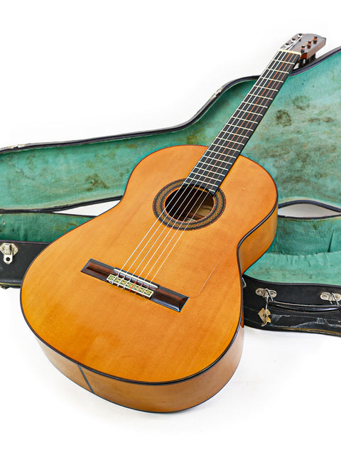 A guitar placed inside a case on a white backdrop, featuring the inscription "M.G. Contreras Calle Mayor 80 - Spain 1973."

