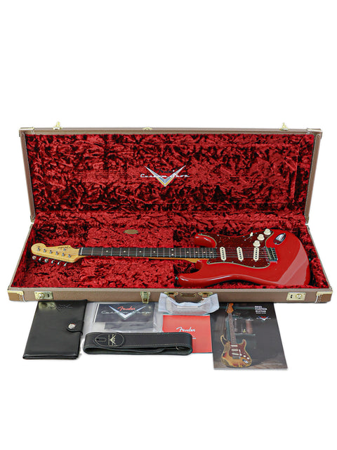 A red Fender Custom Shop 1961 Stratocaster Hardtail guitar in a case, complete with accessories, highlighting its classic design.