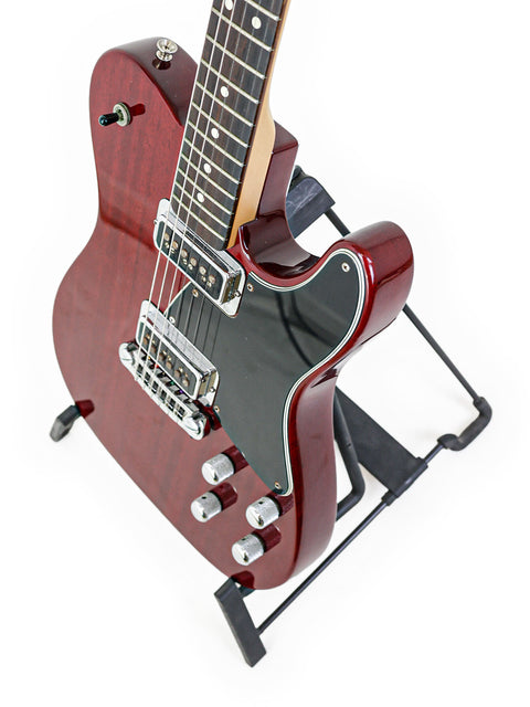A red Fender Tele-Sonic guitar from 2001, displayed on a black stand, showcasing its vibrant color and sleek design.