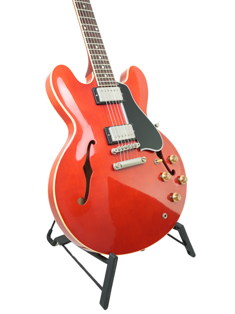 A red Gibson Custom ES-335 Aged '59 Reissue electric guitar displayed on a stand, showcasing its vintage design.