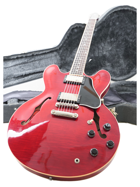 A red Gibson ES-335 Dot guitar from 2006, elegantly placed in its case on the floor, ready for a jam session.