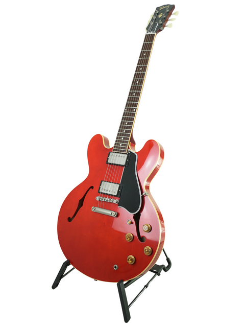 A red guitar, the Gibson Custom ES-335 Aged '59 Reissue from 2018, elegantly positioned on a stand for display.