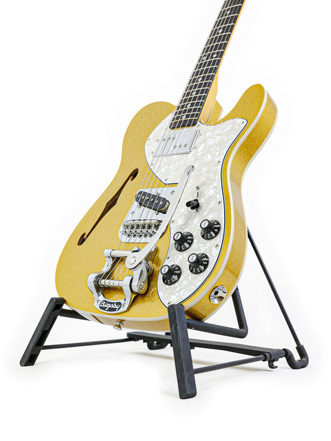 A sleek Txxx Custom Thinline '72 Partscaster guitar on a stand, highlighted by a simple white background.
