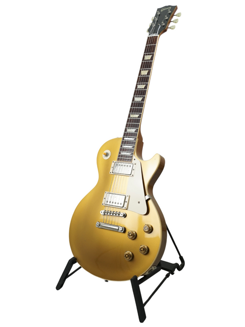 A sleek gold electric guitar resting on a stand, highlighting the Gibson Custom Shop LPR-7 1957 Les Paul Goldtop Reissue, USA 2003.