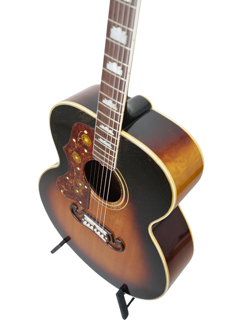 A stunning 1955 left-handed Gibson J-200 guitar showcased on a stand, contrasting beautifully with a white background.