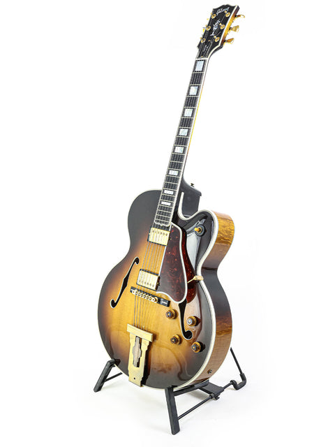 A stunning Gibson L-5 CES guitar displayed on a stand, set against a pristine white background for a striking visual appeal.