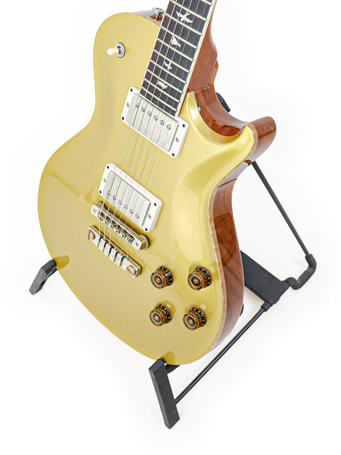 A stunning golden electric guitar, the PRS McCarty Singlecut 594 from 2020, elegantly positioned on a stand.
