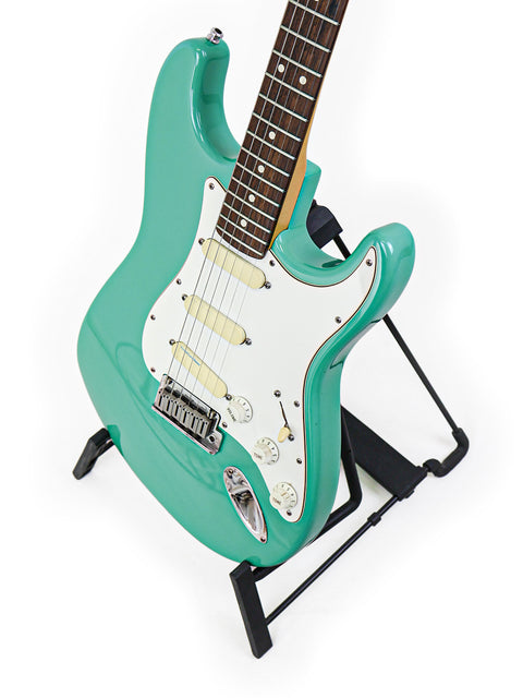 A vibrant green electric guitar, the Fender Strat Plus Deluxe from 1989, elegantly positioned on a stand.
