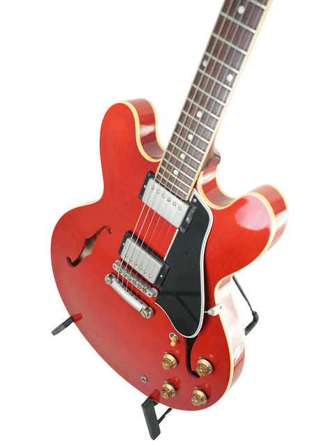 A vibrant red Gibson Custom ES-335 Aged '59 Reissue electric guitar resting on a stand, highlighting its classic style.