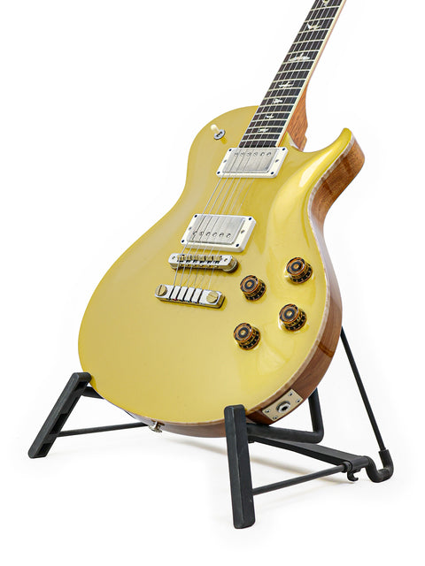 A vibrant yellow electric guitar, PRS McCarty Singlecut 594, elegantly positioned on a stand, ready for performance.