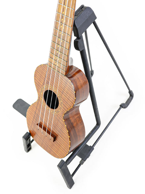 A vintage 1920s Kumalae ukulele resting on a stand, highlighting its unique Hawaiian design.