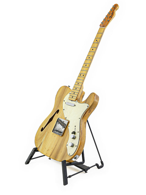 A vintage 1971 Fender Telecaster Thinline guitar resting on a stand, contrasted beautifully with a bright white background.