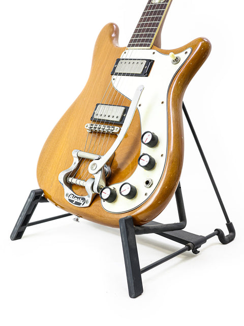 A vintage Epiphone Crestwood Custom guitar from 1964 on a stand, highlighted by a plain white background.