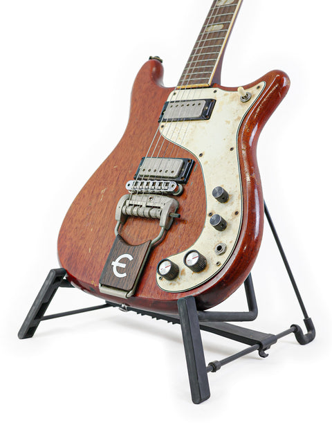 A vintage Epiphone Crestwood Custom guitar from 1966 on a stand, highlighted by a plain white background.
