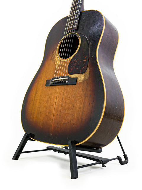 A vintage Gibson J-45 acoustic guitar from 1953, proudly positioned on a stand, embodying classic musical artistry.