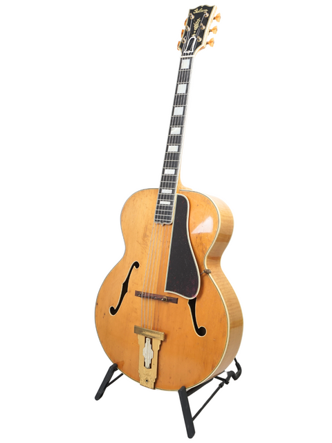A vintage Gibson L-5 from 1939 on a stand, contrasting with a plain white background.