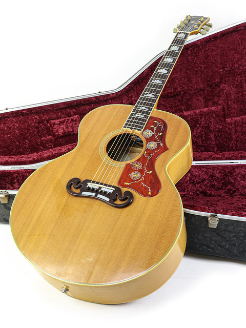 A vintage Gibson SJ-200 guitar nestled in a red case, representing its iconic style from the USA, 1984.