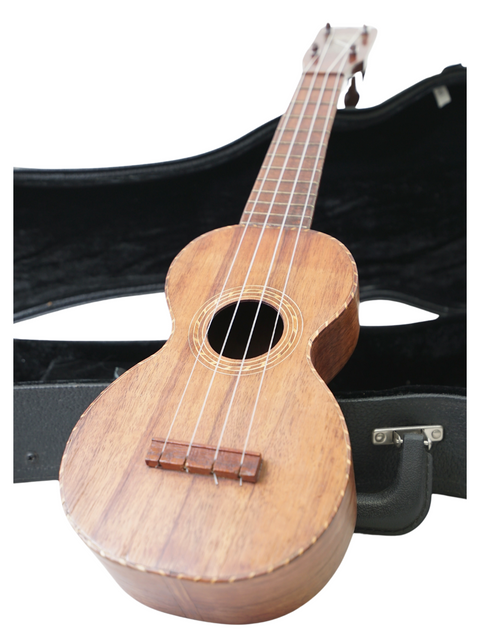 A vintage Kumalae Model D ukulele rests in its case against a white background, highlighting its Hawaiian heritage from c.1920.