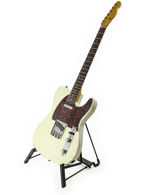 A vintage L Series Fender Telecaster, white in color, elegantly positioned on a stand with a black base.