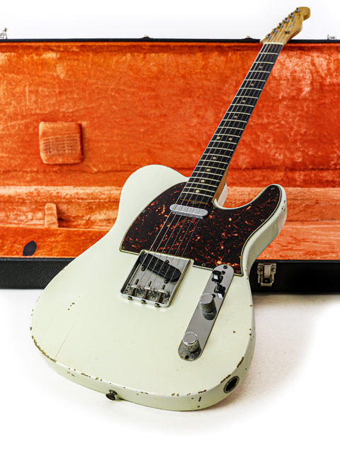 A vintage L Series Fender Telecaster, white with a black pickguard, housed in an orange case.
