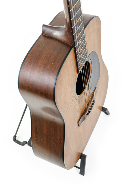 A vintage Martin D-18 guitar from 1974 on a stand, showcased with a white background.