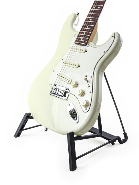 A white 2008 Fender Custom Shop Jeff Beck Signature Stratocaster guitar on a black stand, highlighting its elegant design.