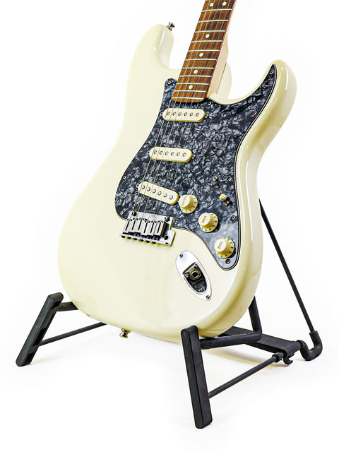 A white Fender Jeff Beck Signature Stratocaster guitar displayed on a black stand, highlighting its classic and stylish look.