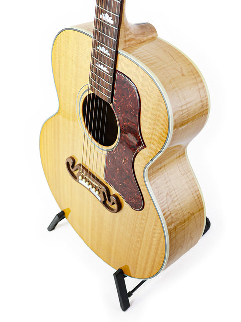 A white background highlights a Gibson SJ-150 guitar from 2008, elegantly positioned on a stand.