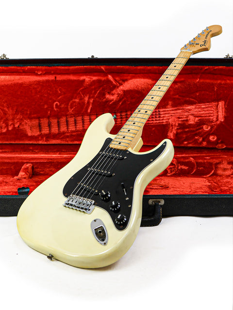 A white electric guitar, the vintage 1977 Fender Stratocaster, safely stored in its stylish case.