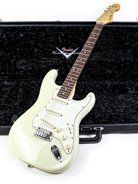 A white guitar, the Fender Custom Shop Jeff Beck Signature Stratocaster, resting in a stylish black case.
