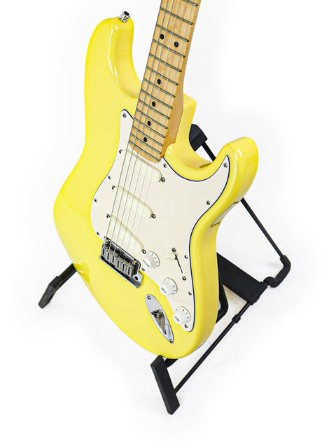 A yellow electric guitar with a maple neck on a black stand, white background.