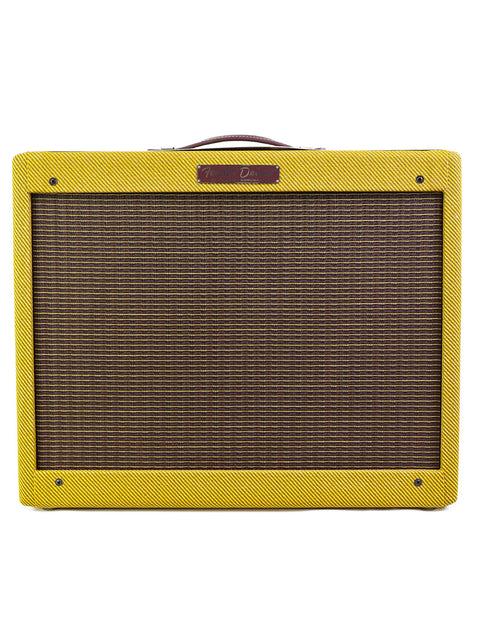 A yellow guitar amplifier with a dark grille and a "Fender Deluxe" logo on top.