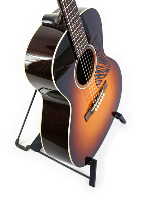 Acoustic guitar on a stand against a white background.